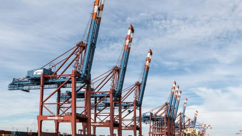 Industrial cranes at European port under cloudy sky
