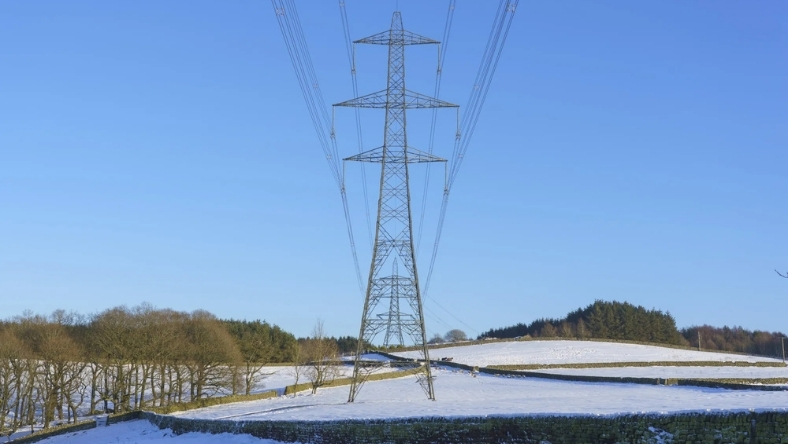High-voltage transmission tower carrying power lines across rural landscape