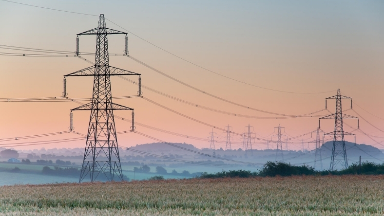 High-voltage electricity transmission towers across rural landscape