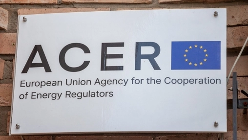 White sign reading ACER European Union Agency for the Cooperation of Energy Regulators beside an EU flag