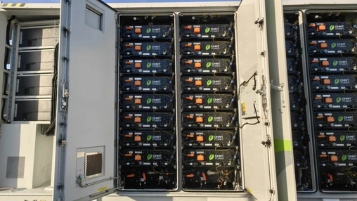 Open cabinet with stacked CHNT Power battery storage modules and orange connectors inside a BESS enclosure