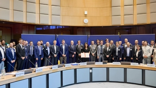 Group of professionals in a circular European Commission meeting room with EU flags for a formal photo