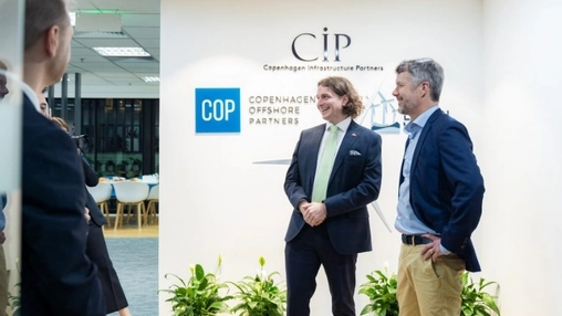 Two business executives stand and converse beneath CIP and COP branding in a corporate office lobby