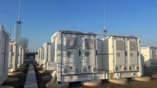 White containerised battery energy storage units installed in a row at an outdoor utility-scale facility