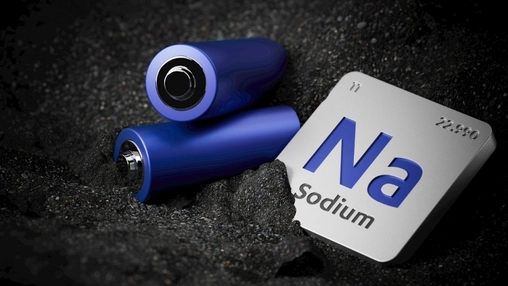 Blue cylindrical cells on dark granular surface beside a silver periodic table tile showing Na and Sodium