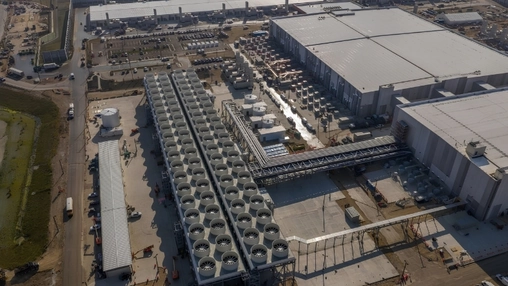Aerial view of a data centre complex with two long rows of large rooftop cooling units and warehouse buildings