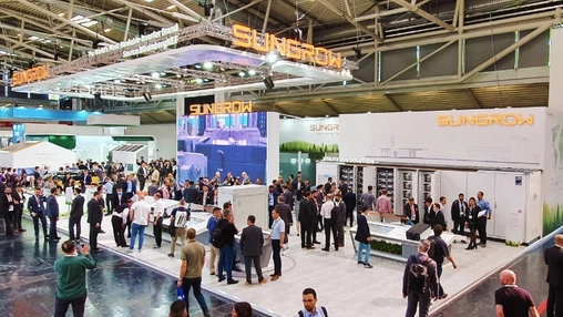 A large Sungrow exhibition stand with orange branded signage and visitors browsing energy storage displays